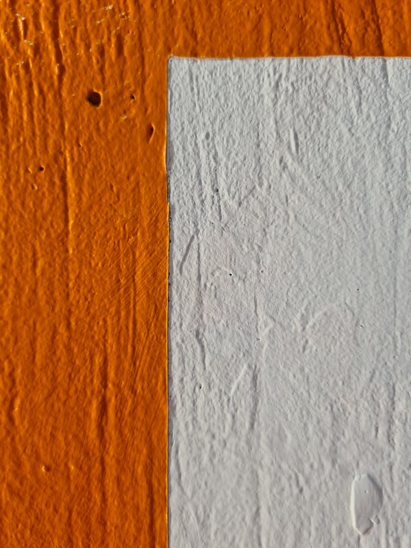Orange paint on white concrete wall. The wall is textured with lines. The boarder edge of the orange paint is straight and beginning to peel slightly. 