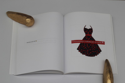 A book held open on a white table with golden skatestops as paper weights, left page reads "Interview went well smiley", right page shows a picture of a red and black dress and a red banner across the middle with white text that reads "Giveaway comment to win....." and a white star shape