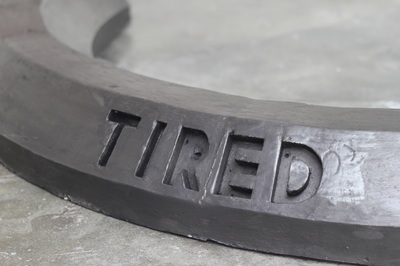 Black crescent shaped car stop with enscribed word "Tired" in campital letters