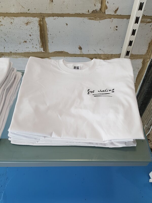 Neat pile of folded white t-shirts with the words "for washing" embroidered on it