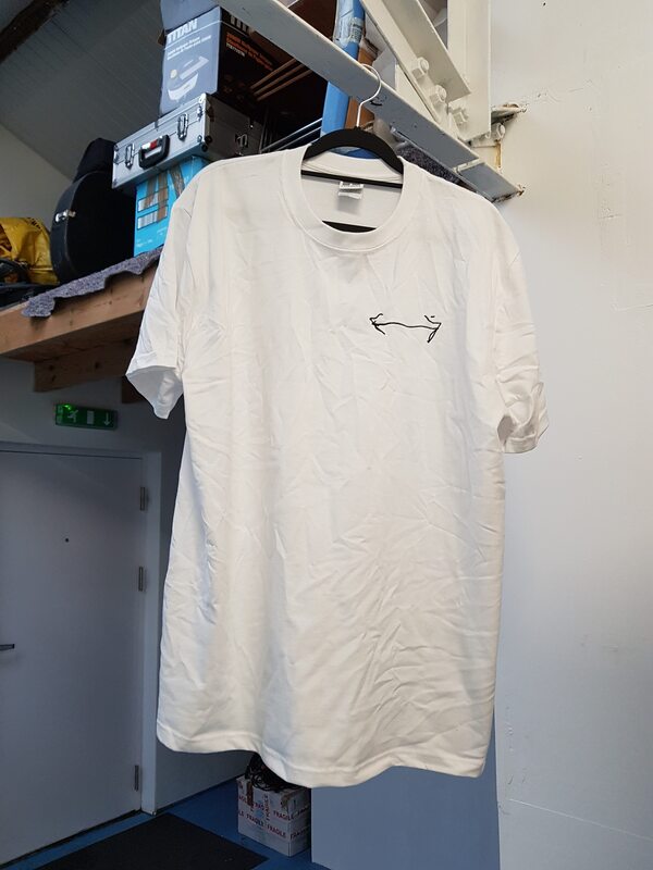A white t-shirt on a coat hanger hung from a metal girder, the t-shirt has a double headed arrow embroidered on it