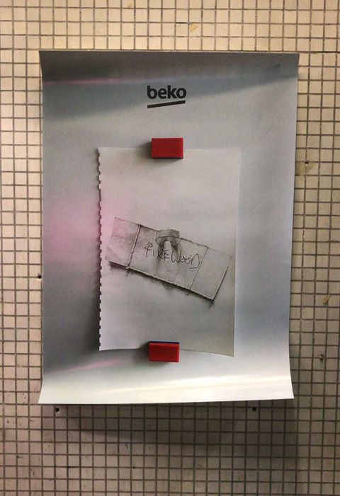 Poster stuck to a wall, the poster shows a drawing stuck to a fridge, the drawing is of a note stuck with a magnet, the note reads "firewood"