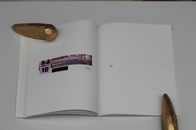 A book held open on a white table with golden skatestops as paper weights, left page shows a banner with a cropped Mean Girls poster which reads "Totally Grool" and a profile picture with a pink background and purple text reads "Mean Girls 10th" and white text reads "anniversary", right page shows a heart emoji and "x"