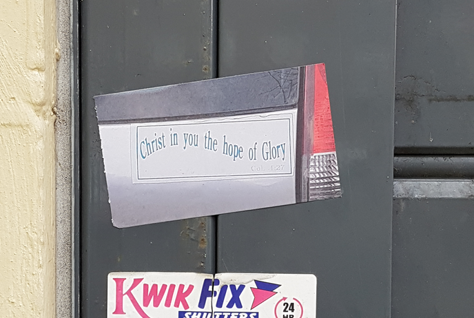 Sticker artwork depicting the back of a silver car with a white bumper sticker with wavy blue text reading 