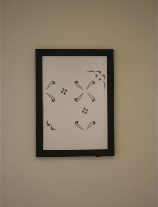 Reversed pattern of collaged skate stop pictures on white A4 paper in black frame hung on white wall