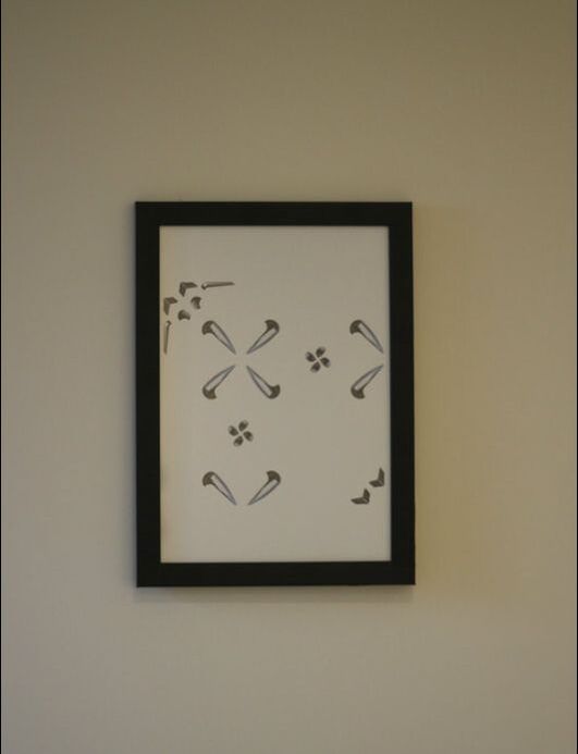 Pattern of collaged skate stop pictures on white A4 paper in black frame hung on white wall