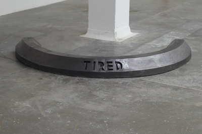 Black crescent shaped car stop with the word "Tired" enscribed