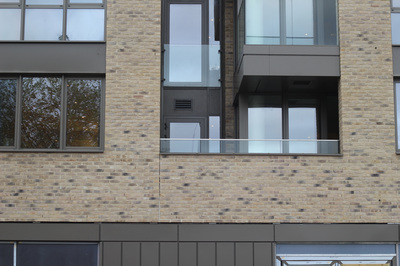 Two golden skate stops along the grey ledge of a beige brick balcony of a modern luxury flat 
