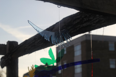 A blue translucent cut out of a fern hanging from a wire