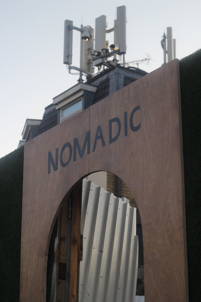 Top of the flat wooden archway with the word "Nomadic" painted in black across the top